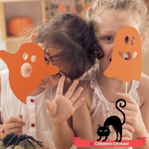 Children's Orchard Halloween promotion with two little girls holding arts and crafts paper ghosts on sticks