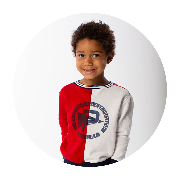 Preschool aged boy wearing a red and white Ralph Lauren sweatshirt.